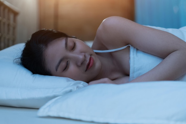 美しい若いアジアの女性は深く眠っていて、美しい夢を持っています