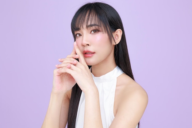 Beautiful young Asian woman model long hair with natural makeup on face clean skin on isolated violet background Cute girl portrait Facial treatment Body care Beauty and Spa