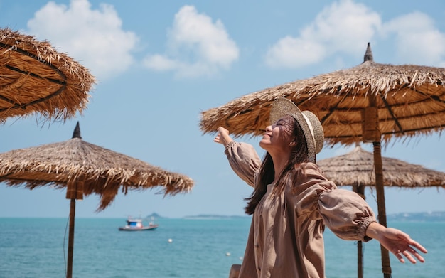 해변에서 휴가를 즐기면서 손을 드는 아름다운 젊은 아시아 여성