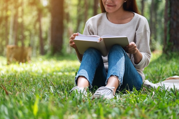 A beautiful young asian woman reading a book while sitting in the park