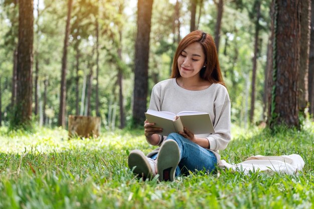 公園に座って本を読んでいる美しい若いアジアの女性