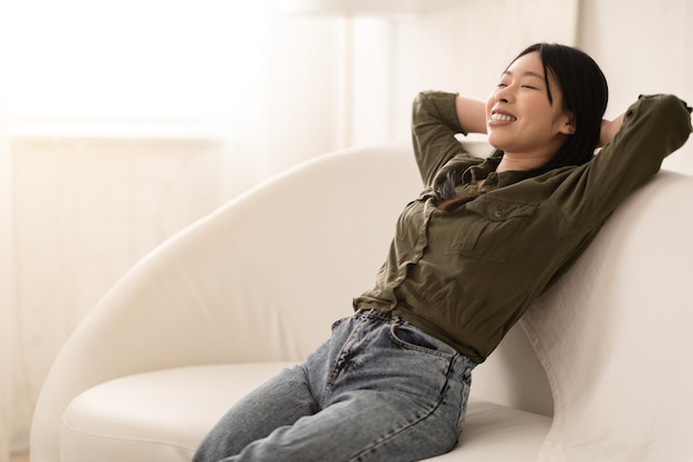 写真 リビング ルームのソファでリラックスした美しい若いアジア女性