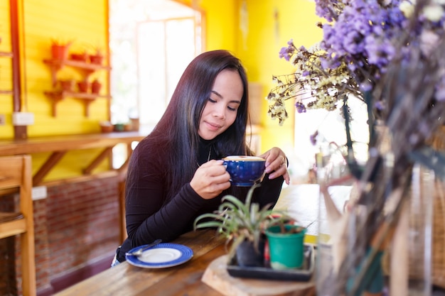 Beautiful young asian woman relaxing with coffee cup at coffee shop