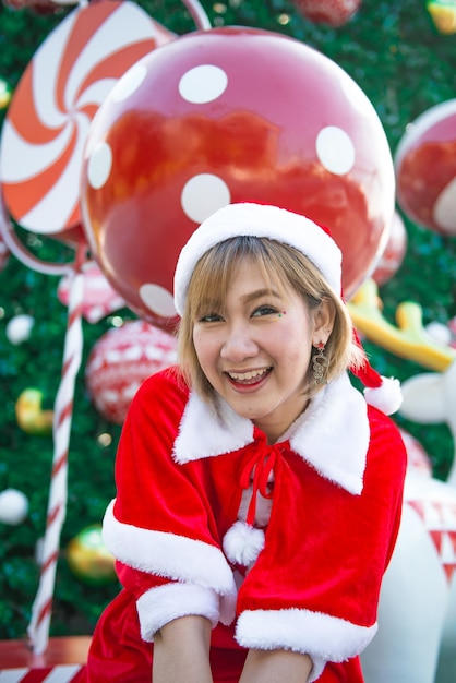 Красивая молодая азиатка в одежде Санта-Клауса на открытом воздухе