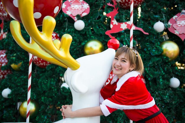 Beautiful young asian woman in Santa Claus clothes outdoorsThailand peopleSent happiness for childrenMerry christmasWelcome to winterDecorated christmas background