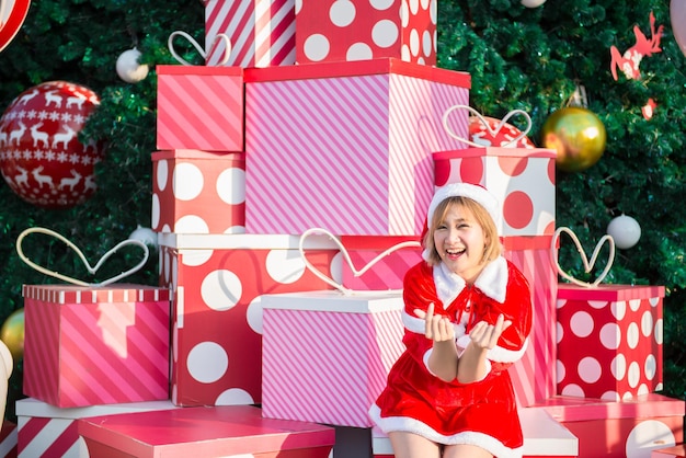 Beautiful young asian woman in Santa Claus clothes outdoorsThailand peopleSent happiness for childrenMerry christmasWelcome to winterDecorated christmas background