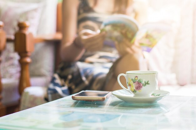 Beautiful young asian woman sitting on chair relaxing coffee time with book and smartphone at home