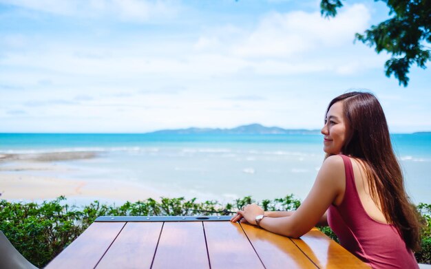 A beautiful young asian woman sitting and looking at the sea and blue sky