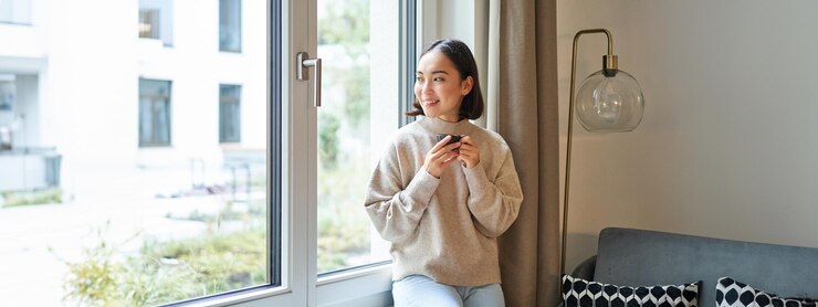 Photo 美しい若いアジアの女性が窓の近くに座って、エスプレッソ カップとコーヒーを飲みながら