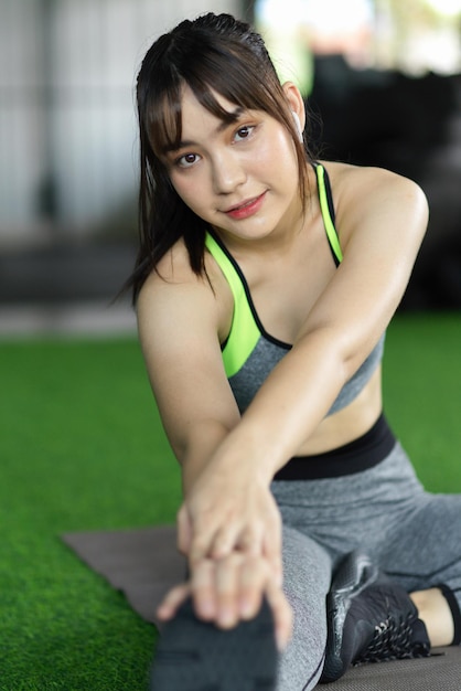 Beautiful young asian woman in sportswear stretching her legs muscular after cardio exercise.