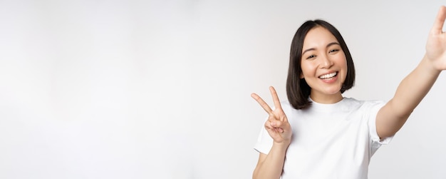 Beautiful young asian woman taking selfie posing with peace vsign smiling happy take photo posing ag