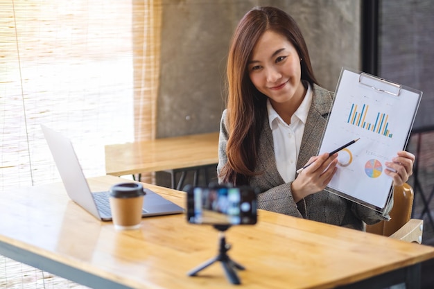 A beautiful young asian woman teaching business class online with laptop computer on the table