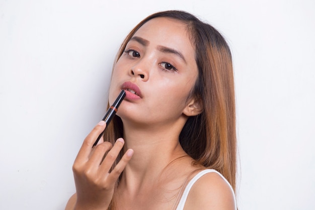 beautiful young asian woman using lipstick isolated on white background