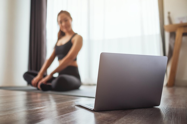 A beautiful young asian woman watching online workout tutorials on laptop at home