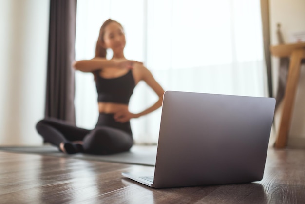 A beautiful young asian woman watching online workout tutorials on laptop at home