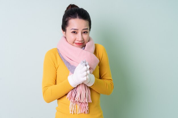 Beautiful young Asian woman wearing sweater on green background