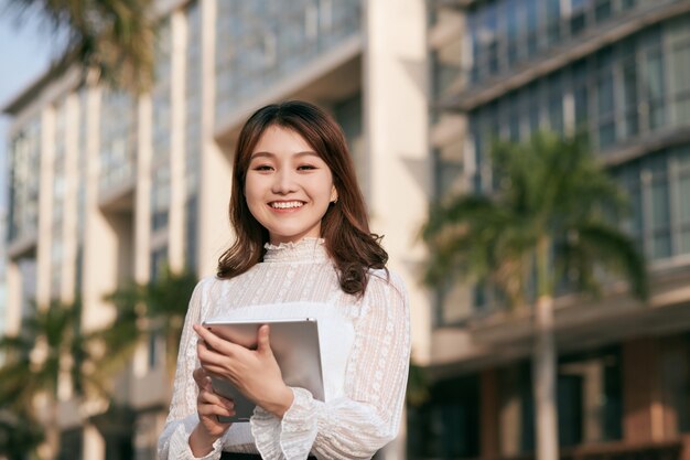 タブレット コンピューターを見る美しい若いアジア女性