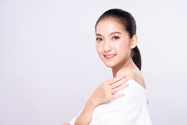 Photo beautiful young asian woman with clean fresh white skin face in beauty pose touching shoulder with finger