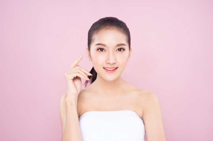 きれいな新鮮な白い肌の美しさのポーズでそっと自分の顔に触れる美しい若いアジア女性。
