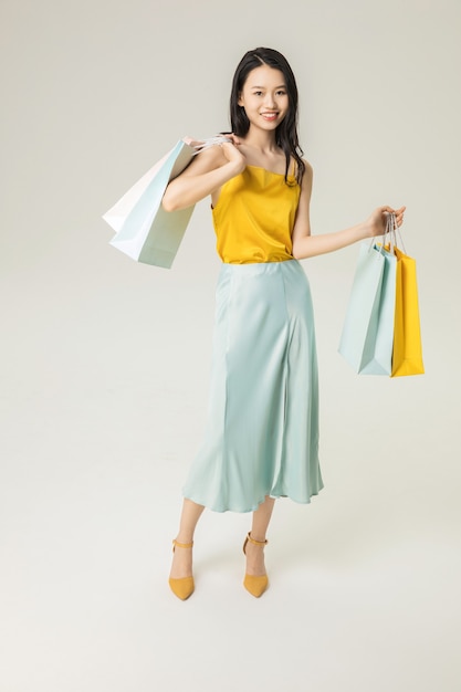 Beautiful young Asian woman with shopping bags isolated