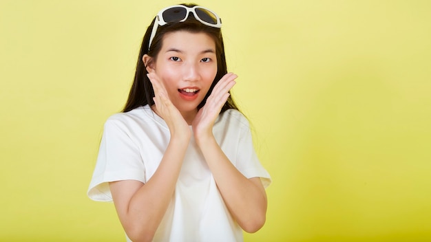 Красивые молодые азиатские женщины удивлены солнцезащитными очками на голове на желтом фоне