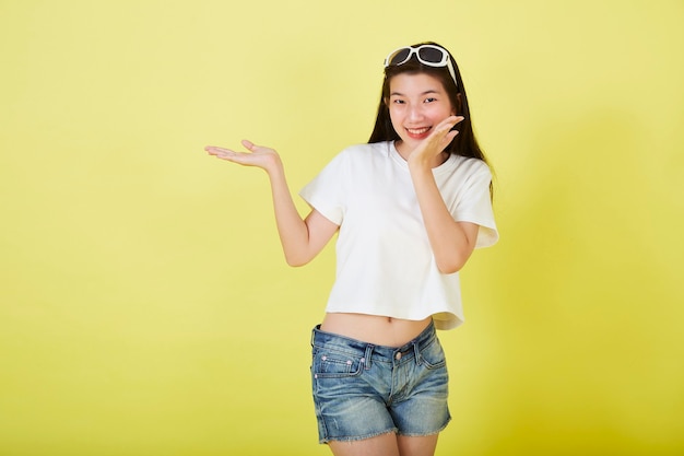 Beautiful young Asian women with sunglasses on her head on yellow background