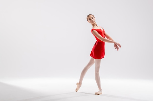 Beautiful young ballerina on a white background The ballerina is dressed in a red leotard pink leotards pointe shoes