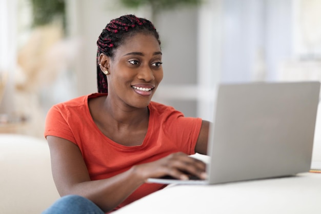 Photo beautiful young black woman using laptop while sitting at desk at home