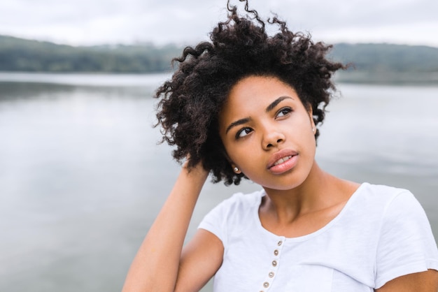 텍스트 또는 광고 콘텐츠를 위한 복사 공간이 있는 자연 배경에 대해 수심에 찬 반사 표정을 가진 아름다운 젊은 흑인 여성