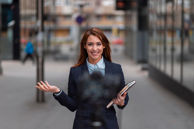 Beautiful young blogger making a video report outdoor