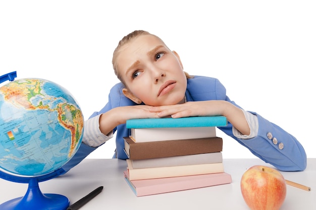 Beautiful young blond student with large pile of books sitting at table and dreaming Isolated over white background