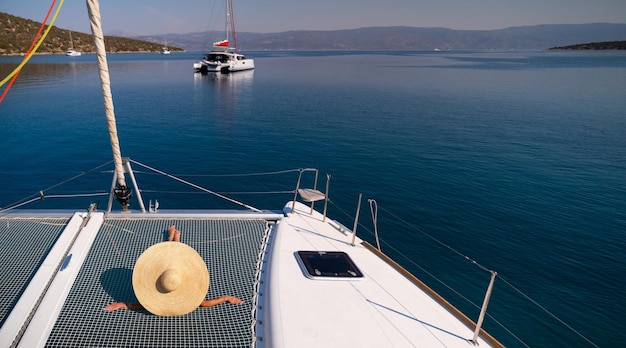 Beautiful young blond woman in bikini laying on catamaran bow at sunny summer day