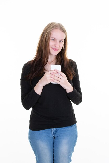 Beautiful young blond woman holding mobile phone on heart in jeans pockets casual smiling beautiful slim girl