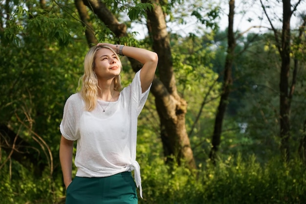 Красивая молодая блондинка в лесу Девушка наслаждается природой