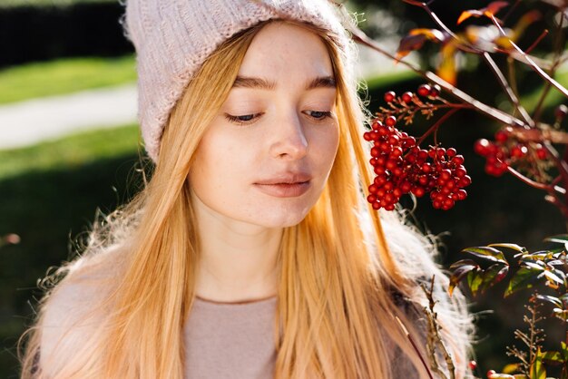 Beautiful young blonde girl in hat walking in the garden, enjoying plants and nature