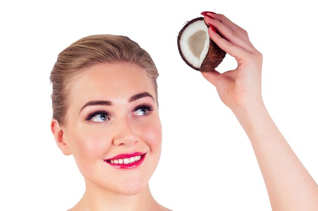 Beautiful young blonde hairstyle girl with a long eyelashes make-up red lipstick on lips and perfect skin with coconut in her hand in the studio on a white background. Beauty face.