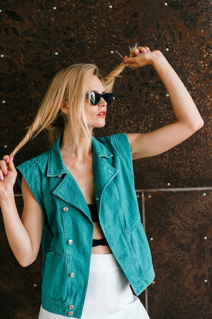 Beautiful young blonde model in stylish clothes posing in studio