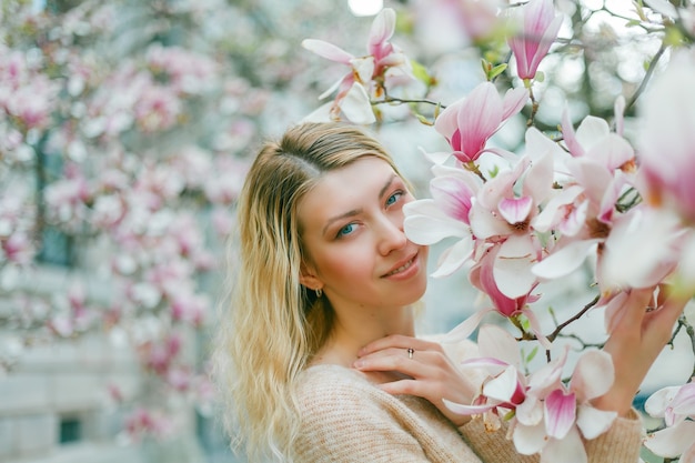 開花マグノリアの木の近くの美しい若いブロンド