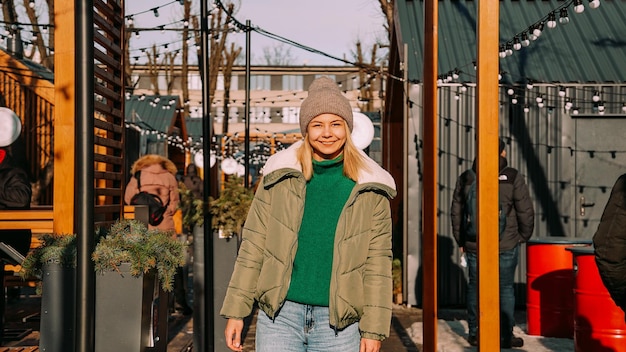 Beautiful young blonde woman looks up with a smile while standing outdoors