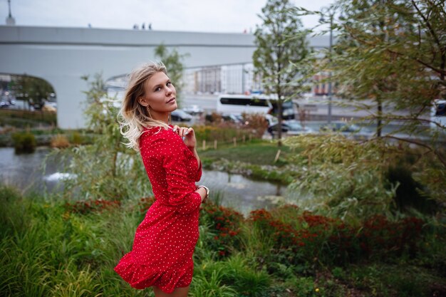 A beautiful young blonde woman in a pretty short red dress walks in the center of Moscow. The central places of the city. 