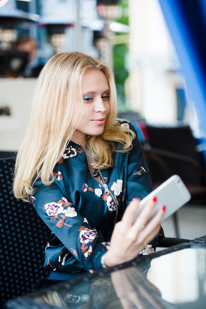 Красивая молодая блондинка делает селфи со смартфоном на открытом воздухе