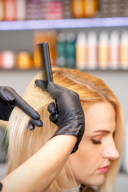 Beautiful young blonde woman with long straight blonde hair getting a haircut at the hairdresser salon