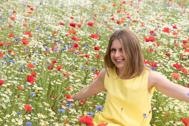 Foto una bella giovane donna bionda in un vestito giallo si trova tra un campo fiorito