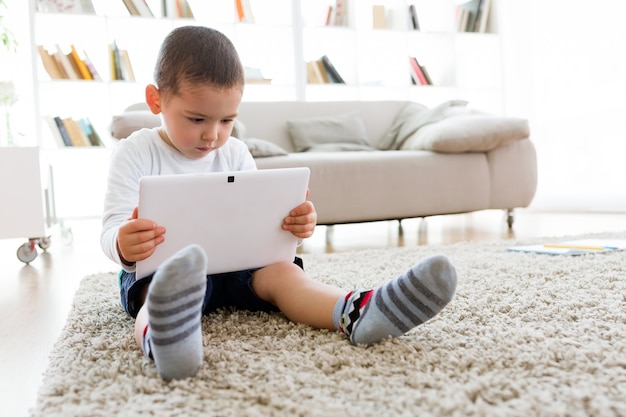 Beautiful young boy using his digital tablet at home.