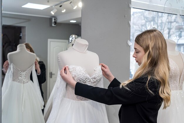 Beautiful young bride choosing perfect wedding dress in store\
for her best day concept of chosen the right dress