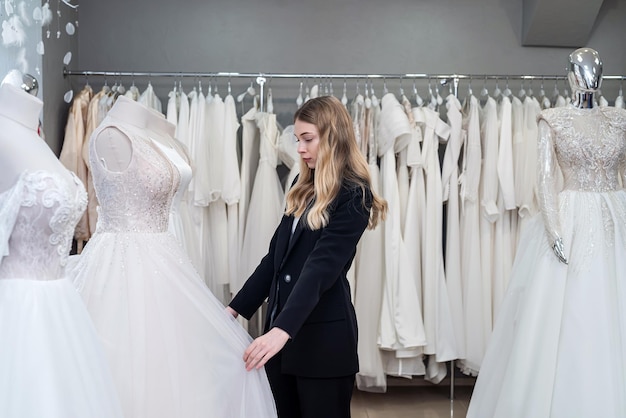 Красивая молодая невеста выбирает идеальное свадебное платье в магазине для своего лучшего дня Концепция выбора правильного платья