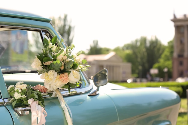 Beautiful young bride holding bouquet in decorated car outdoors