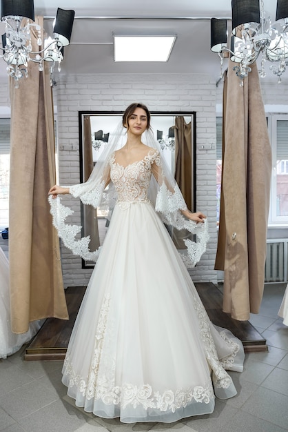 Beautiful young bride posing in wedding dress in salon