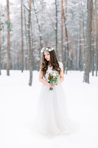 Beautiful young bride in the winter snowy forest