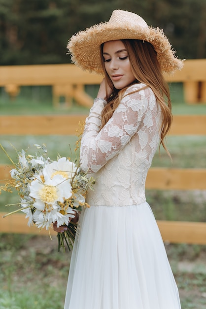 A beautiful young bride with a bouquet of daisies in a field